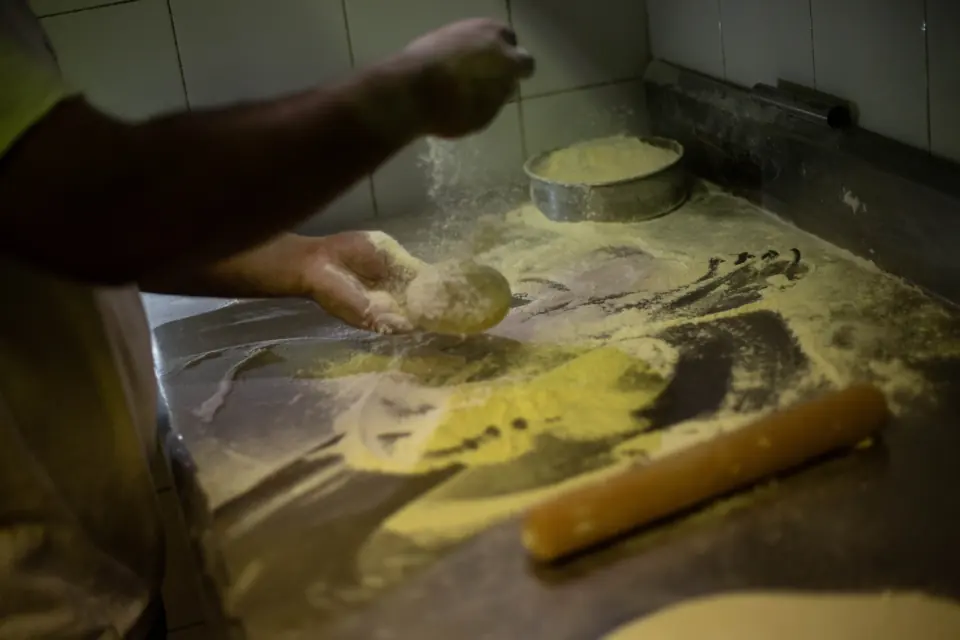 Mani che lavorano l’impasto infarinato sul banco